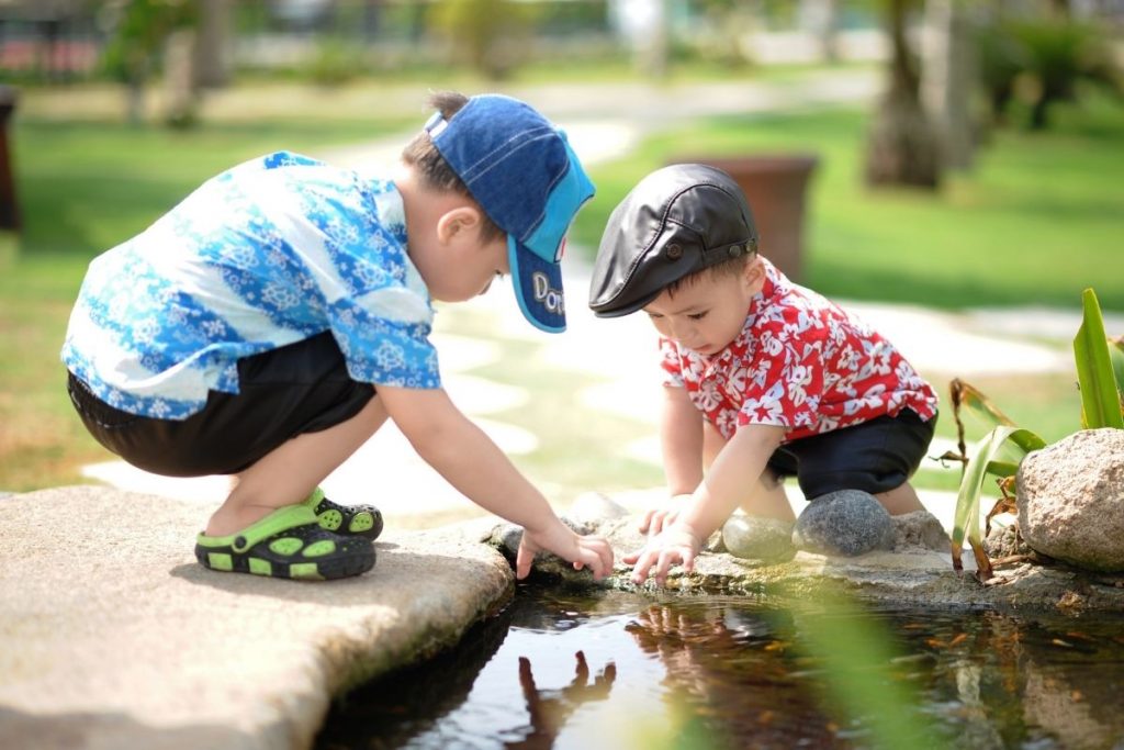 two young boys playing in pond