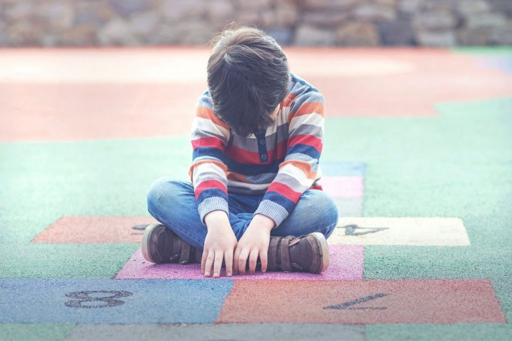 boy looking down while sitting on play mat
