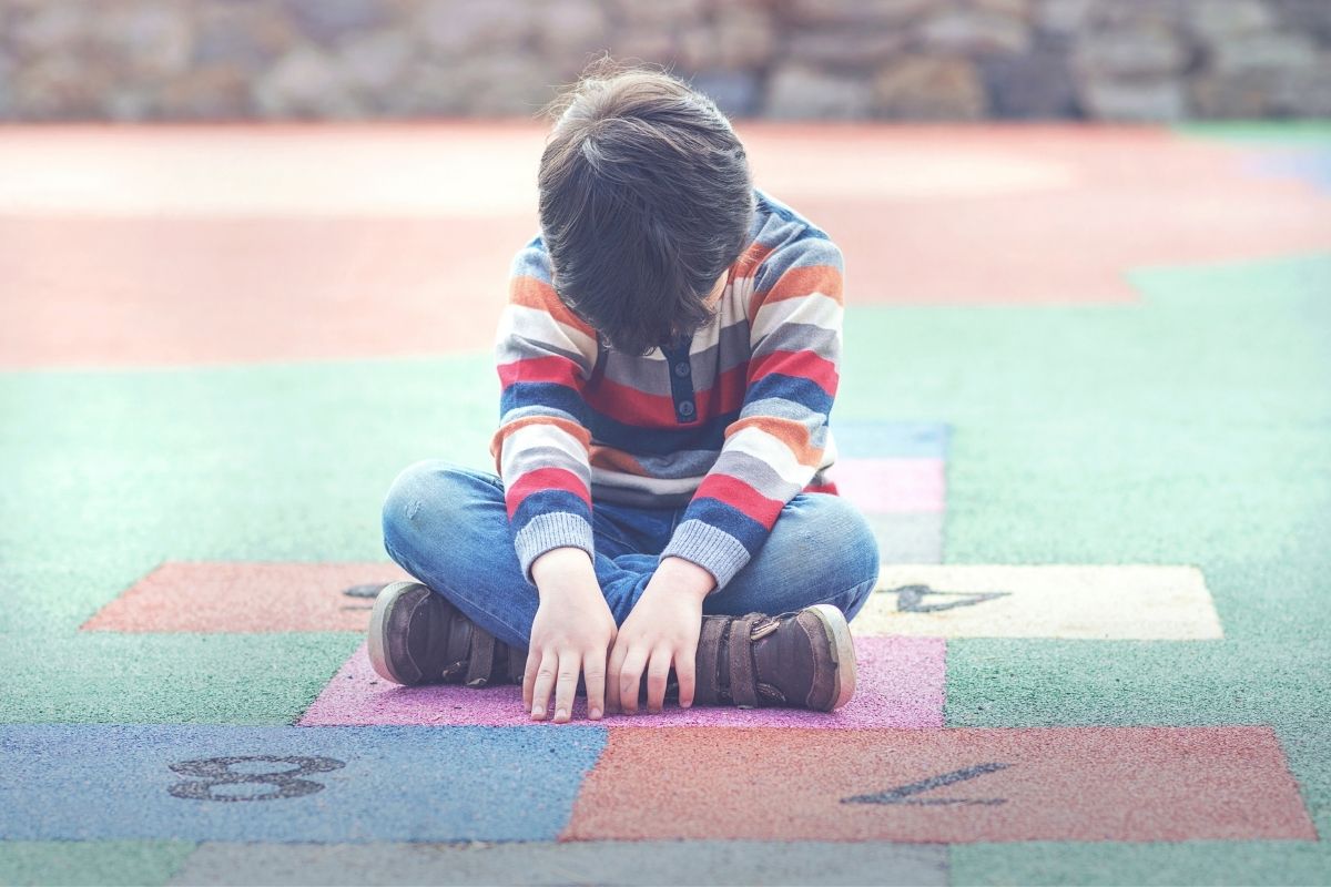 boy looking down while sitting on play mat